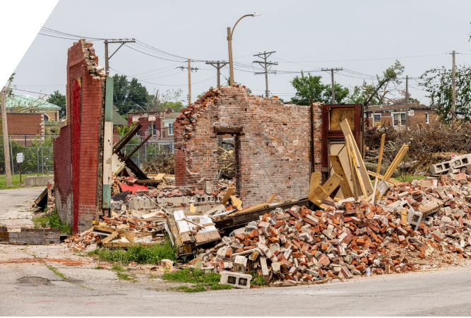 Remains of a brick building stand amidst a large pile of rubble in a St. Louis neighborhood.