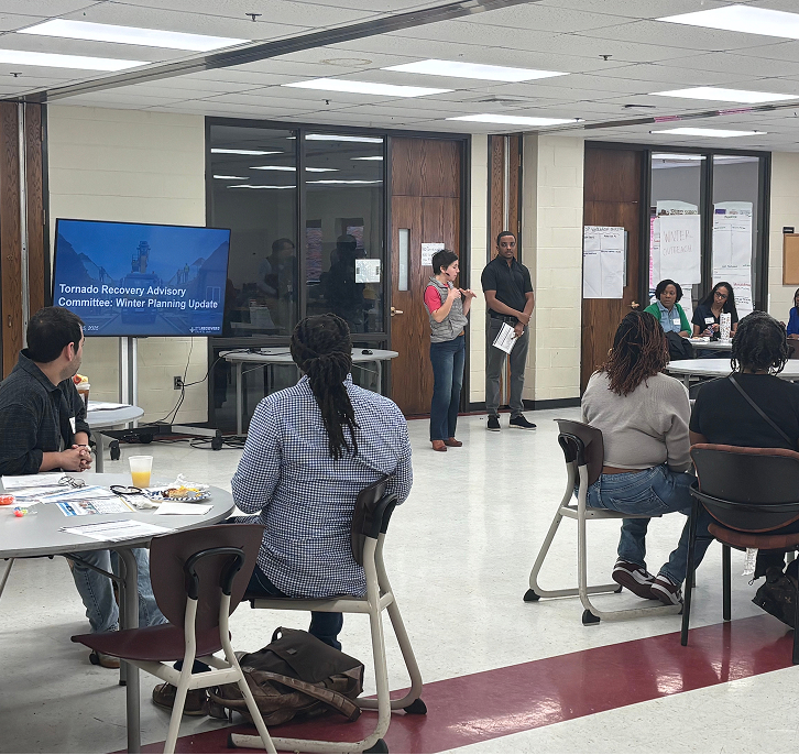 St. Louis Mayor Cara Spencer speaks at a Tornado Recovery Advisory Committee meeting, with a presentation slide titled "Winter Planning Update" visible in the background.